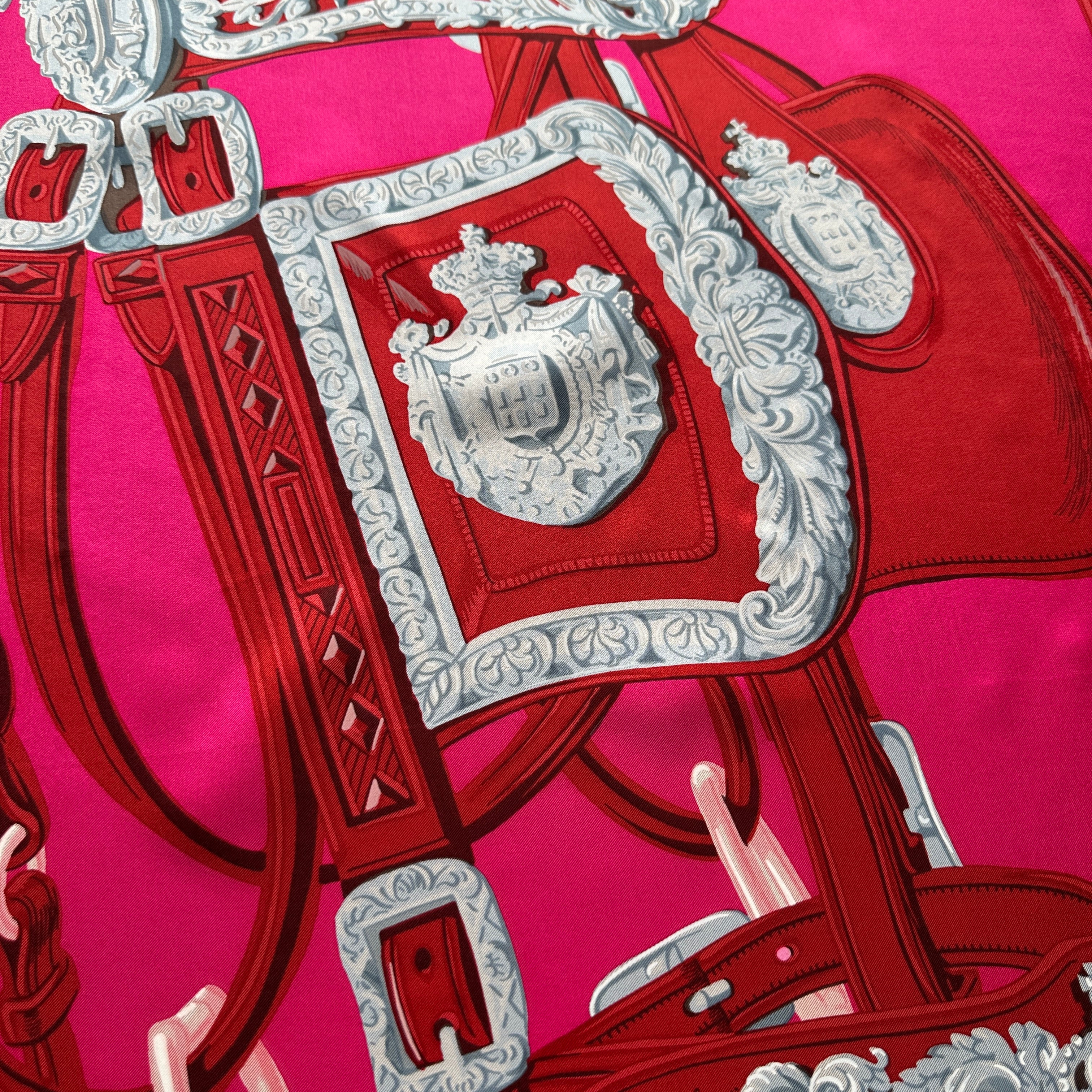 Détail écusson sur le châle Brides de Gala Hermès, couleur fuchsia.