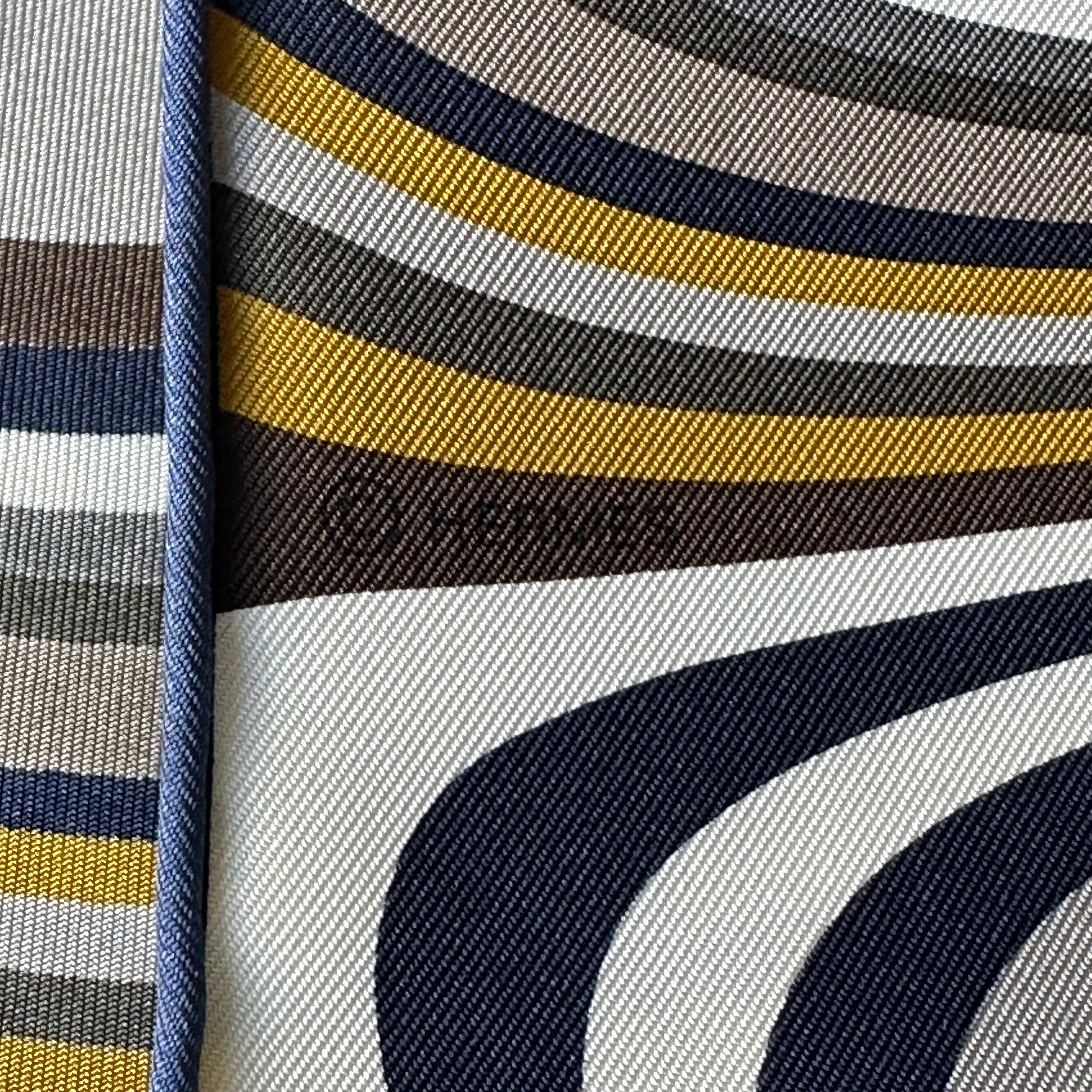 Mention du copyright "© HERMÈS" discrètement intégrée dans les rayures graphiques du foulard.