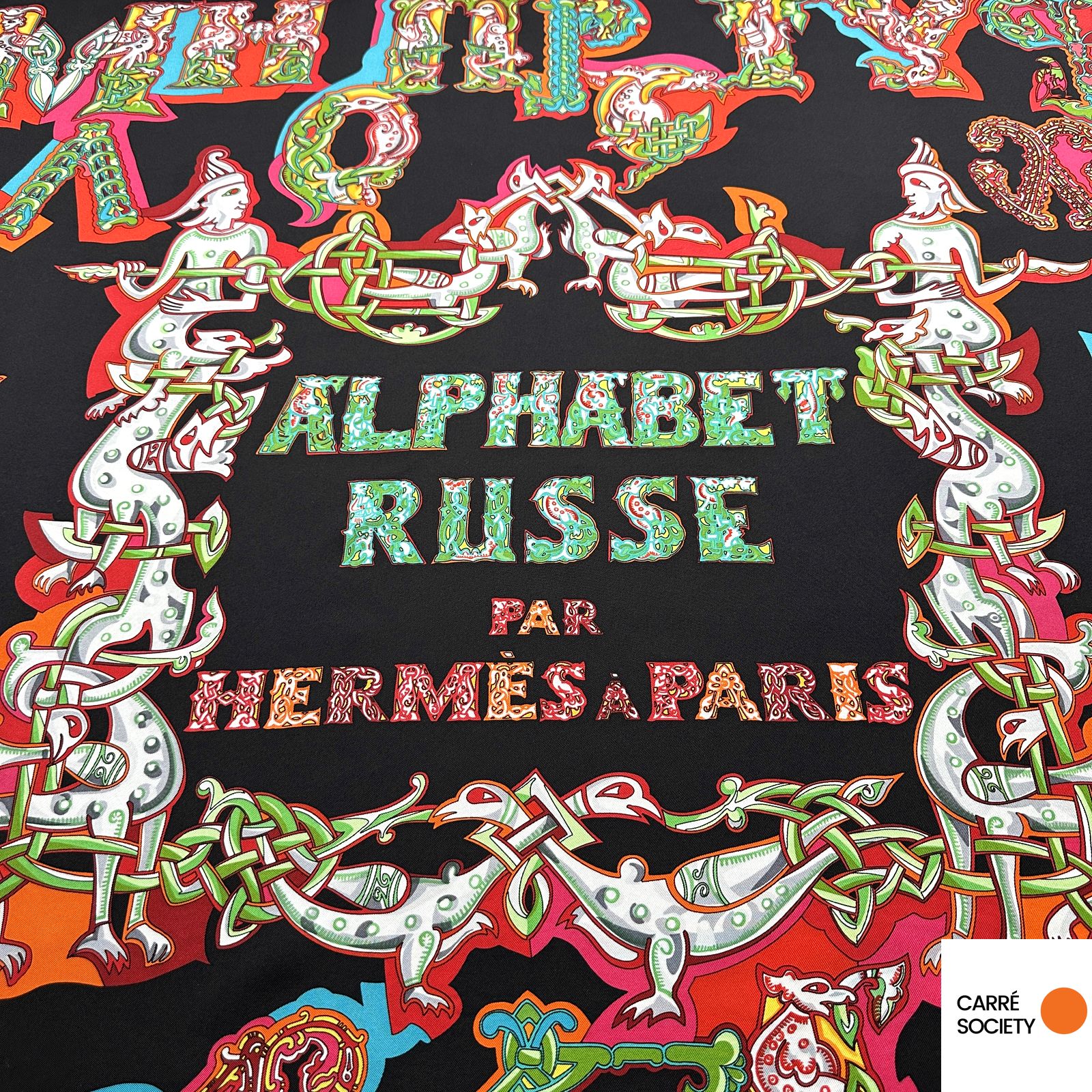 Détail du centre du carré : inscription « Alphabet Russe par Hermès à Paris » entourée d’un motif entrelacé rouge et vert.