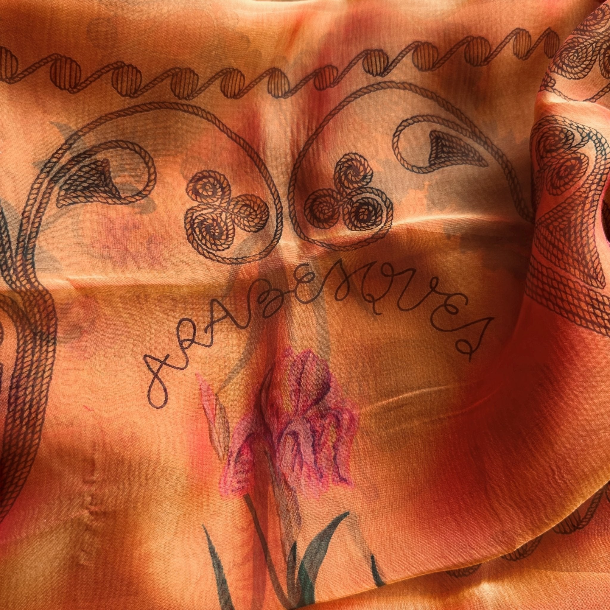 Gros plan sur le titre "ARABESQUES" intégré dans le motif du foulard Hermès.