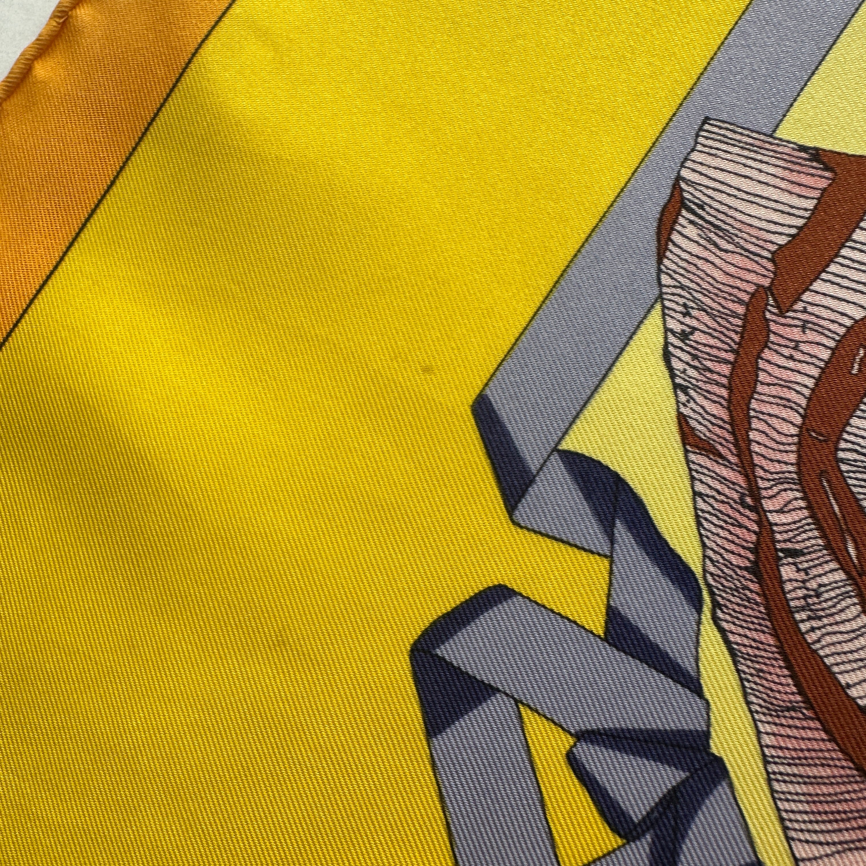 Vue rapprochée montrant une légère trace d'usage ou tache diffuse sur la soie jaune solaire du carré Hello Dolly.