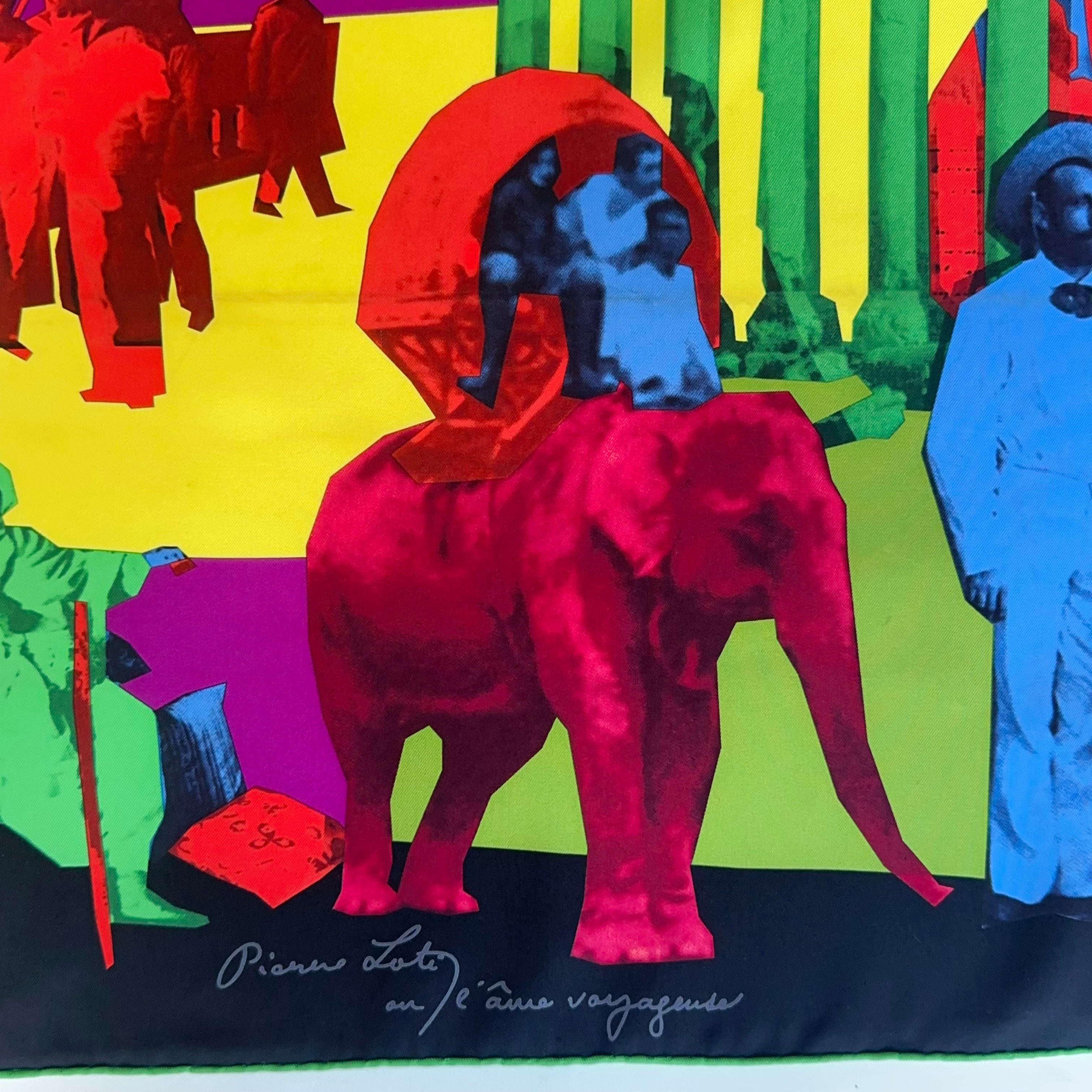 Gros plan sur le bas du foulard : éléphant rose portant des voyageurs et titre manuscrit "Pierre Loti ou l'âme voyageuse" sur le bord roulotté noir.